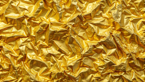 Seamless gold leaf background texture. Shiny golden yellow crumpled metallic foil repeat pattern.