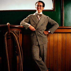 Harold Lloyd, classic silent film actor, in a herringbone suit. Standing confidently against a stark white backdrop.