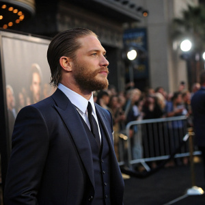 Tom Hardy, actor, deep in thought. Dark suit and tie. Crowd at the Hollywood premiere.