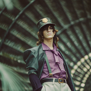 Jotaro Kujo, the indomitable hero, captured in a high-definition photograph. His strong build is highlighted by a stylish cap with gold embellishments and a vibrant purple shirt. Set against a vivid, black background, the image is further enhanced by an intricate design that adds depth and emphasis to Jotaro's imposing presence.