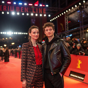 Wanda Badwal and Felix Rachor at Berlinale. Wearing trendy outfits. Against bright lights and bustling crowds.