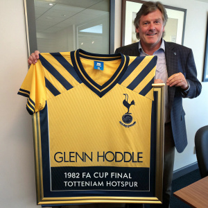 Glenn Hoddle's 1982 FA Cup Final Tottenham Hotspur jersey framed with gold inlay. Signature and team logo on display. Yellow and navy blue stripes visible.