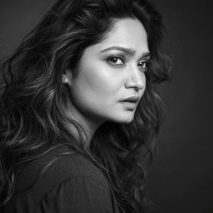 Ankita Lokhande, South Asian actress, serious look, long wavy hair, profile shot. Dark, blurred background, black and white photo
