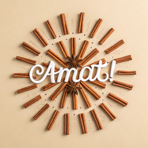 Amat!, a brand logo featuring a sunburst pattern crafted from wooden sticks resembling cinnamon. The white font contrasts sharply against the light beige background, surrounded by intricate wooden details.