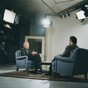 Clint Eastwood appearing on Jimmy Kimmel Live. Seated on a blue velvet chair. Jimmy Kimmel interviewing him.