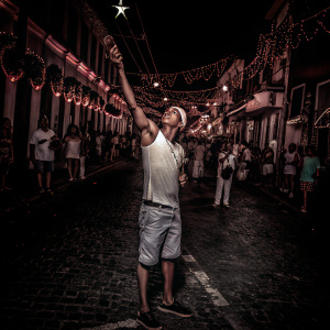 Neymar Jr., donning a casual outfit, poses at the bustling street festival. Surrounded by vibrant decorations and festive crowds.