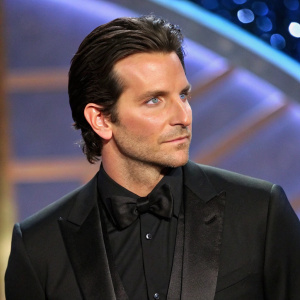 Bradley Cooper at a glitzy awards show. Wearing a sleek black suit, dark hair neatly styled. Serious expression
