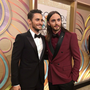Jared Leto, in a black tuxedo, and Jamie Reed, in a maroon blazer, at the Golden Globe Awards. Abstract wall art backdrop.