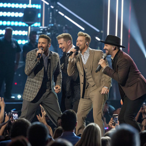 Backstreet Boys, in vintage suits, at a Billboard Music Awards ceremony. A sea of flashing cameras and excited fans in the background.