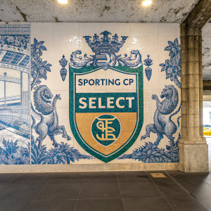 A vibrant azulejo mural showcasing Sporting CP's emblem. The design features intricate blue and white patterns. The central logo reads 'SELECT' prominently. The background is filled with a rich tapestry of sculptural and tiled elements.