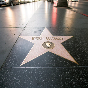 Whoopi Goldberg's star on the Hollywood Walk of Fame. Glowing golden star embedded in dark pavement, centered, surrounded by twinkling lights.