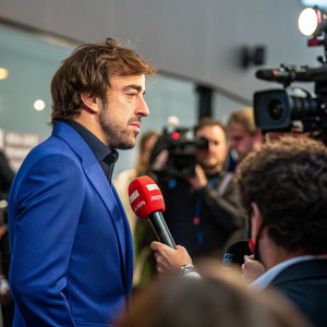Spanish racing driver Fernando Alonso in a press conference, wearing a blue suit. Question and answer session