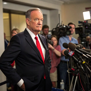 Bill O'Reilly at a press conference. Wearing a dark suit, red tie, and white shirt. Serious expression.