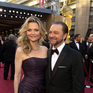 Michelle Pfeiffer and Fisher Stevens gracing the Oscars red carpet, posing elegantly with Hollywood's elite as their backdrop.
