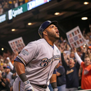 Jesús Aguilar, baseball player, in intense pose. Gray jersey with team logos. A cheering crowd at a baseball stadium