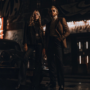 Clara Paget and Toby Huntington-Whiteley, stylish duo, posing for magazine shoot. Neon lights and graffiti background.