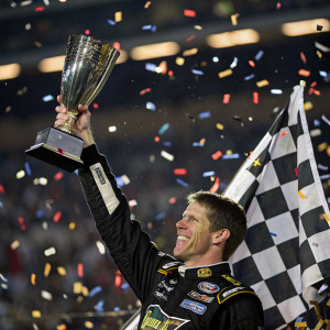 Carl Edwards, celebrating his NASCAR victory. Wearing a checkered flag and holding a trophy. Amidst a sea of confetti and欢呼雀跃的氛围。