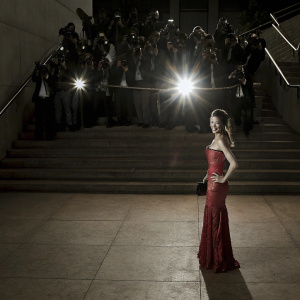 Clara Lee at Cannes Film Festival premiere. Wearing a stunning red dress. Paparazzi flashing in the background.