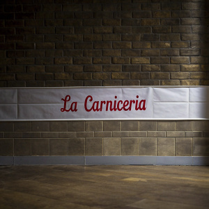Minimalistic logo design for La Carniceria. Bold, cursive red font on a plain white backdrop.