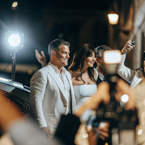 Candid photo of Monica Bellucci, Matt Damon, and a third man at an awards show. Dark background with flashes of cameras
