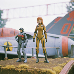 Asuka Langley Sohryu in a detailed action figure pose, alongside a miniature Shinji Ikari. Neon Genesis Evangelion exhibition backdrop