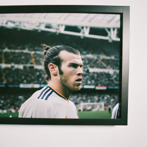 Gareth Bale, Real Madrid star, intense look. Stadium crowd in background. White jersey with blue and gold trim.