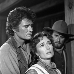 Michael Landon and Anne Archer from 'Little House on the Prairie.' Kevin Hagen in the background. Michael comforts Anne in a tense indoor scene. Black and white photo