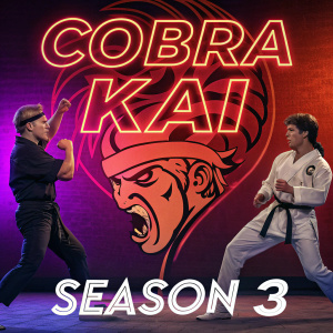 Promotional poster for Cobra Kai season 3. Centered angry face surrounded by two karate fighters in combat stance. Vibrant neon hues of red and purple dominate the background. Bold graphic text overlays.