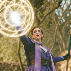 Moira O'Deorain, from Overwatch, in a fierce pose, holding a glowing orb. Background is a swirling vortex of mystical energy.