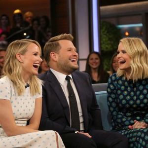 James Corden, Kristen Bell, and Dianna Agron on a talk show set, laughing and chatting. Studio audience in background