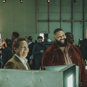 Bobby Kotick and DJ Khaled at a gaming convention. Smiling for the cameras amidst a crowd of gamers and esports enthusiasts.