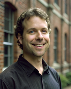 normal looking man with earrings in front of brick building smiling