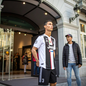 Cristiano Ronaldo's wax figure stands outside the Madame Tussauds museum. The figure wears a Juventus jersey with the iconic number 7 and Nike logo. A mannequin dressed in casual wear stands beside him.