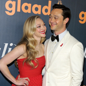 Amanda Seyfried in red dress and Joseph Gordon-Levitt in white suit at GLAAD Media Awards. GLAAD logo in background.