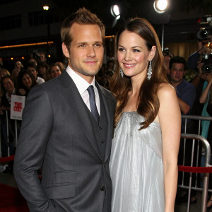 Gabriel Macht and Jacinda Barrett at a Hollywood gala. Gabriel in a dark grey suit, Jacinda in a flowing, silver dress. A sea of flashing cameras and excited fans in the background.