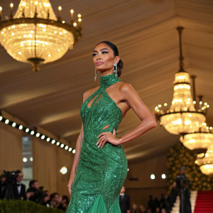 Nicole Scherzinger in a vibrant green dress at the Met Gala. Golden chandeliers in the background.