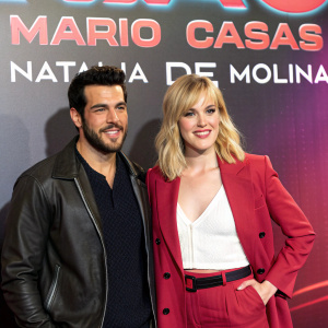 Mario Casas and Natalia de Molina at premiere event. Backdrop featuring bold text and vibrant colors.