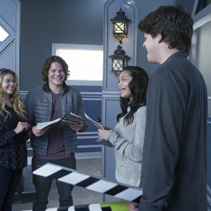 Gage Golightly, Nick Purcell, Malese Jow, and Matt Shively on the set of a Nickelodeon kids' show. Brightly colored set, cheerful atmosphere, holding scripts.