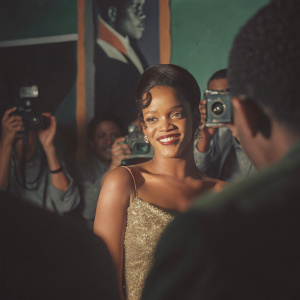 Rihanna, in a sparkling gold dress, poses for photos at the Grammy Awards. Surrounded by flashing cameras and cheering fans.