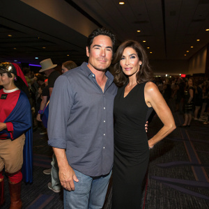 Dean Cain and Teri Hatcher at a Sci-Fi convention. Dean in a casual button-down shirt, Teri in a chic black dress. Crowded hall, dimly lit