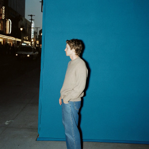 Ole Gunnar Solskjaer, former Manchester United manager, donning a grey sweater and jeans. Surrounded by a bustling street scene with bright neon signs. Nighttime urban backdrop.