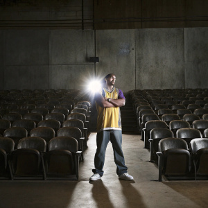 Talen Horton-Tucker, wearing a Lakers jersey, posing confidently in a packed stadium. Flash of camera lights