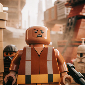 Unkar Plutt, the stern and detail-oriented character from Star Wars, stands with a neutral but intense expression. Wearing a brown, gray, and yellow-black striped tunic. Composed entirely of LEGO elements, he appears against a backdrop of an urban scene from the Star Wars galaxy.