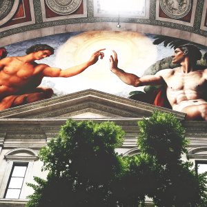 Detailed mural of God reaching out to Adam. Located inside the Sistine Chapel. Ceiling fresco by Michelangelo