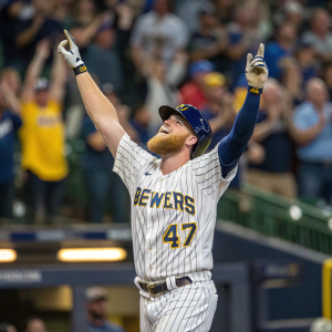 Jett Bandy, celebrating a home run victory. Wearing the official Brewers jersey and number 47. Raising arms triumphantly. A blurred crowd of spectators and a cheering stadium in the background. A moment of pure elation captured.