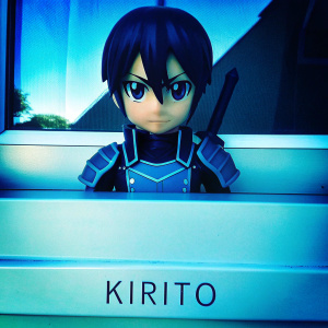 Close-up of Kirito from SwordArtOnline, determined gaze, short black hair. Against white backdrop, his nameplate 'Kirito' visible below