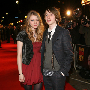 Hannah Murray and Mike Bailey at the 2007 NME Awards. Stylish outfits, red carpet. Bright lights and camera crew in background.
