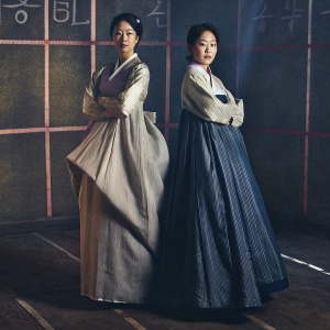 Park Shin-Hye and Jeon Jong-Seo posing at a promotional event for 'Call'. Both wear traditional attire, against a backdrop of simple lines and Asian characters. Dark room with soft lighting.