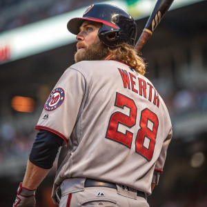 Jayson Werth, intense expression, ready stance. Grey jersey with red accents, number 28 visible. Stadium blurred in background. High-resolution, action-oriented image.