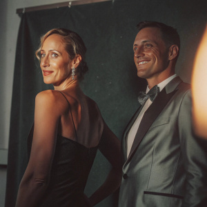 Kim Raver and Manuel Boyer at a book launch party. Elegant attire, standing in front of a simple black backdrop.